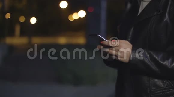 女人的手在一个夜城的背景下握着电话视频的预览图