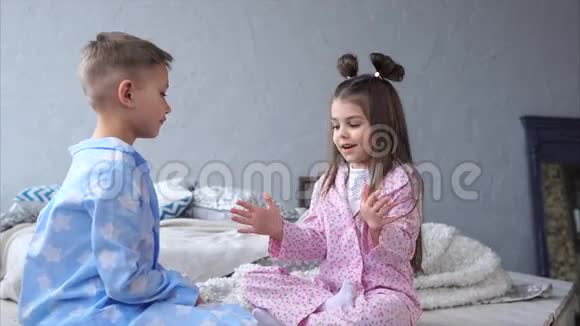 孩子们在卧室里玩小女孩和男孩坐在床上视频的预览图