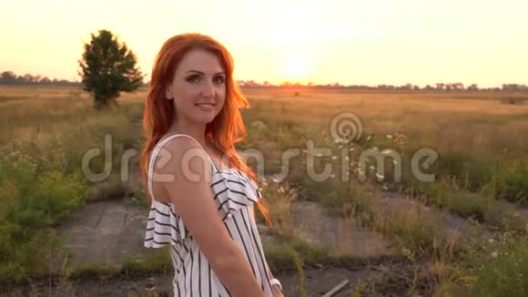 红发女人看着相机对着夕阳微笑视频的预览图