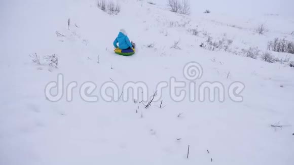 快乐的女孩在雪地里滑下一个充气的雪管挥动她的手美丽的年轻女子滑过视频的预览图