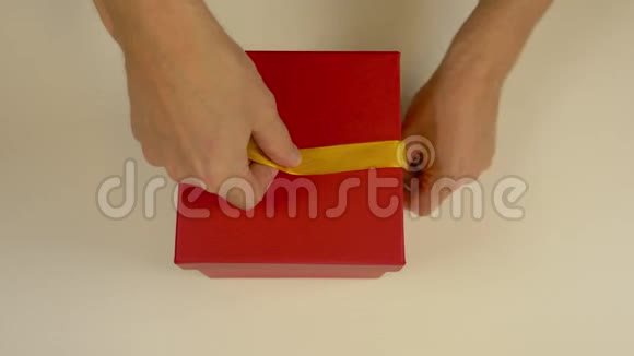 快速运动时间流逝包装红色礼盒白人男子的手包装礼品盒男人的双手系着丝带视频的预览图