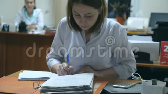 年轻护士在办公室办公桌工作并书写病历女医生在医院开处方视频的预览图