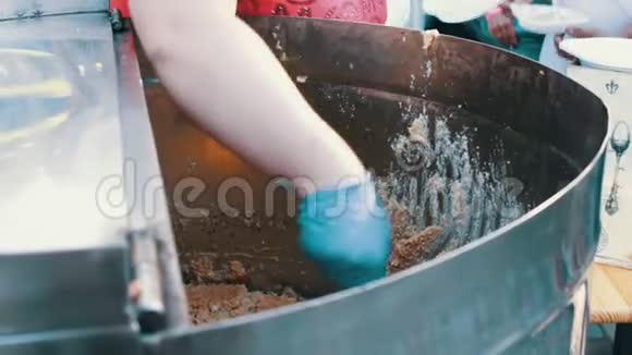 一个女人手把粥从一个大缸里倒进一个塑料盘子里街头美食快餐街头小吃美味视频的预览图