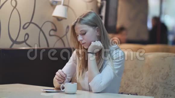 可爱的小女孩手里拿着一杯咖啡酒吧的桌子上放着手机视频的预览图