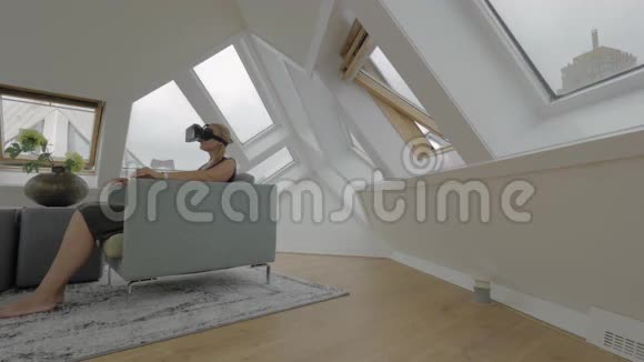 观看年轻的金发女人坐在扶手椅的一侧使用平板电脑在房间内的立方体房子鹿特丹公约视频的预览图