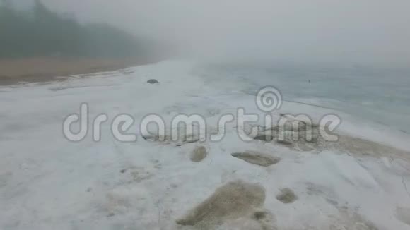 孤独的人走过冰雪覆盖的海洋海岸线视频的预览图
