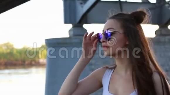 快乐的女人戴着太阳镜在户外跳舞以城市桥和天空为背景视频的预览图