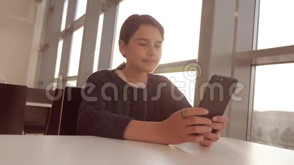 十几岁的女孩的生活方式是在餐桌上的一家咖啡馆里用智能手机与信使聊天视频的预览图