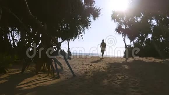 带着背包沿着热带海滩散步的年轻人到达海洋举起手臂男性徒步旅行者前往沙质海岸视频的预览图