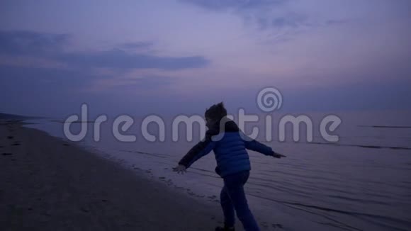 寒冷的一天小男孩在海边玩得很开心视频的预览图