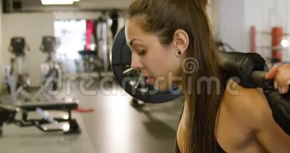 健身馆里一位运动型女子举重训练蹲体的特写镜头视频的预览图
