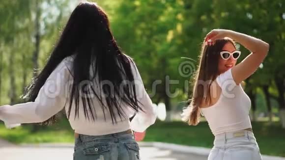 周末两个穿着衣服的漂亮女孩骑在公园的赛格威上一边笑着跳舞视频的预览图