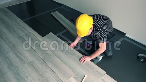 专业男性工人黄色安全帽安装地板视频的预览图