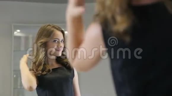漂亮的少女在长着头发的镜子里看着自己视频的预览图