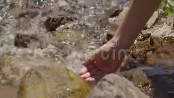 女孩在干净的山间小溪里打水视频的预览图