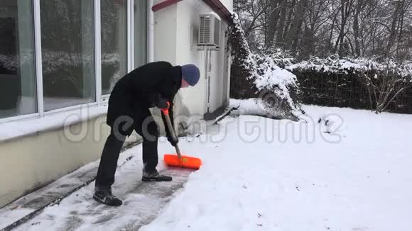冬季公园里工人从房子附近的小路上擦雪4K视频的预览图