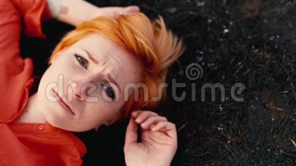 悲伤的女孩红发躺在黑色的大地上悲伤地盯着天空概念需要帮助孤独视频的预览图