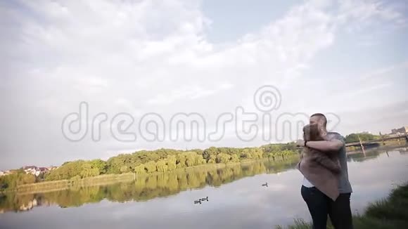 在这座城市的背景下在河边约会的情侣一个男人拥抱一个快乐的女孩视频的预览图
