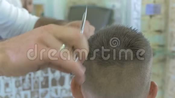 专业发型师在理发店用剪刀剪一个小男孩的头发视频的预览图