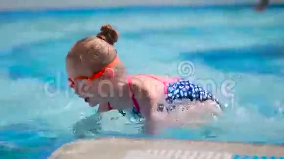 可爱的戴护目镜的小女孩在游泳池游泳视频的预览图