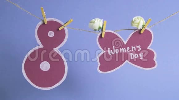 妇女节快乐妇女节纸上装饰着鲜花挂在一根绳子上靠近一张纸编号8蓝色背景视频的预览图
