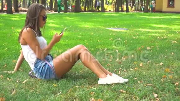 在公园草地上用智能手机的女人视频的预览图