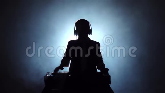 剪影男孩DJ在乙烯基上玩烟熏背景慢动作视频的预览图