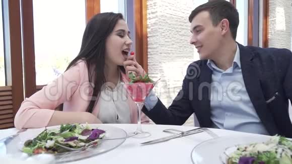 一对情侣在餐馆吃晚饭一个男人用浆果慢动作录像喂一个女孩视频的预览图