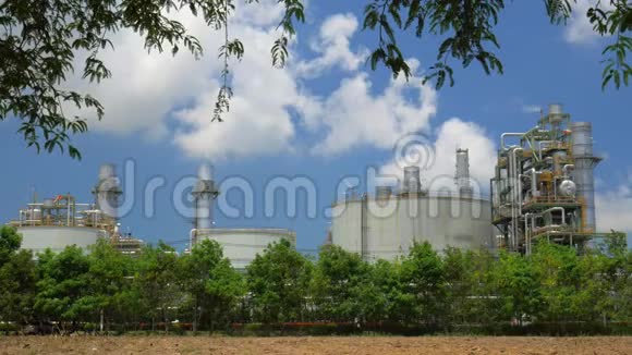 排在树后面的炼油厂和蓝天上的云视频的预览图