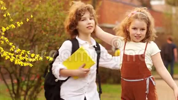 兄妹男孩和女孩在一棵盛开的春天树的背景下拥抱知识日回到过去视频的预览图