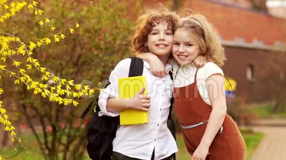 学童兄妹男孩和女孩在一棵盛开的春天树的背景下拥抱日视频的预览图