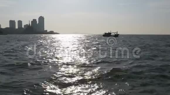 大海中一艘渔船的剪影映衬着阳光明媚的小路泰国亚洲帕塔亚视频的预览图