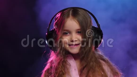 戴着耳机的小女孩在烟雾弥漫的背景下跳舞慢动作视频的预览图