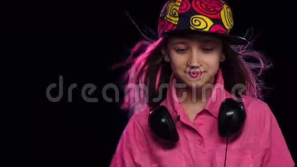时尚女孩带着耳机在脖子上跳舞慢动作视频的预览图
