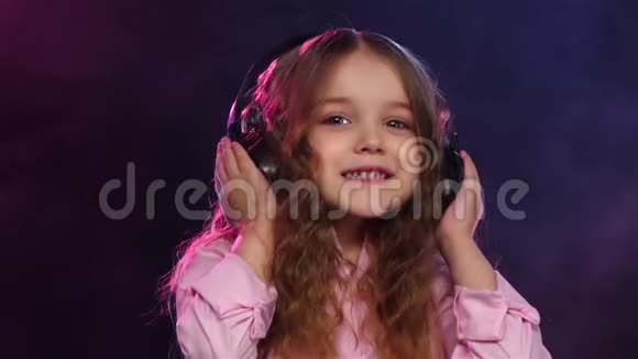 小女孩戴着耳机在烟雾弥漫的背景上跳舞慢动作视频的预览图