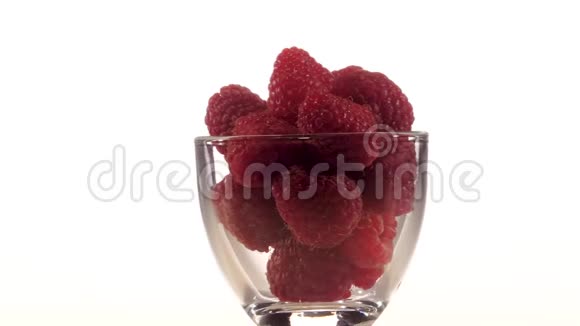 透明杯中的红树莓在白色背景上旋转特写视频的预览图