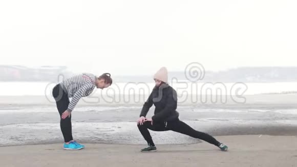 两个运动的女人站在海滩上热身天气寒冷视频的预览图