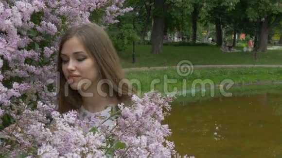 那个年轻的女孩正在享受丁香的香味呼吸着花香视频的预览图