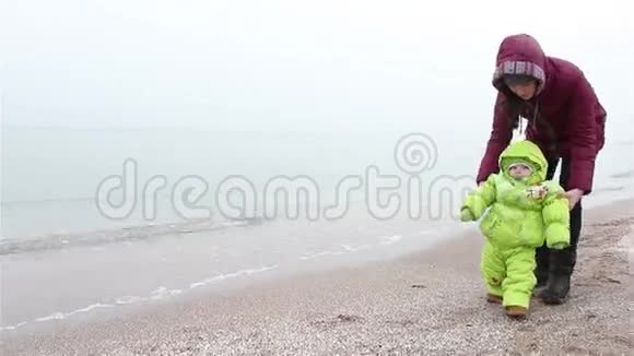 冬天妈妈和孩子一起在海滩上散步视频的预览图