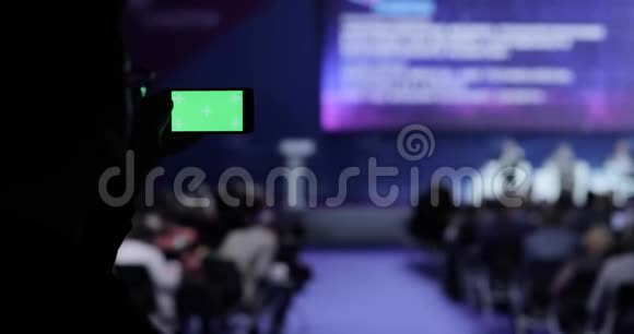 在会议上在移动智能手机上拍摄视频和照片的人绿色屏幕与卢马哑光包括在内商务视频的预览图
