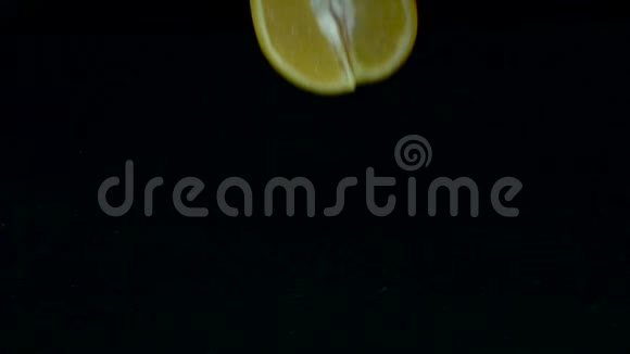 四分之一的橘子掉进水里黑色背景慢动作视频的预览图