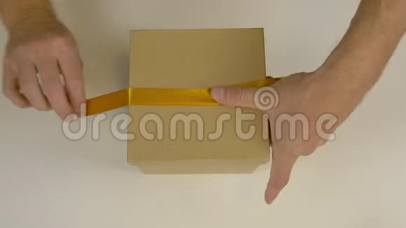 快速运动时间流逝包装礼盒白人男子的手包装礼品盒男人的手系着一条棕色的丝带视频的预览图