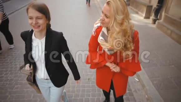 两位年轻漂亮的女士在老城散步说话和微笑的慢动作视频的预览图