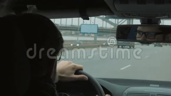 戴眼镜的年轻人在大城市开车视频的预览图