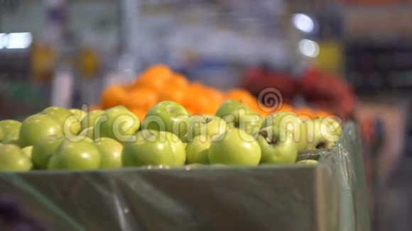 一个女孩在商店的蔬菜货架上挑选绿色的苹果视频的预览图
