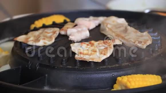 肉培根和条纹猪肉烤在黑色电烤架与玉米煮沸在它的侧面视频的预览图