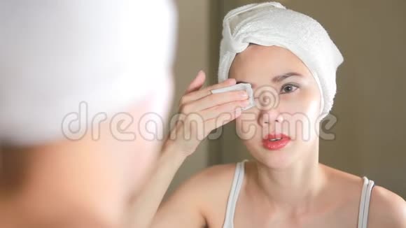 女人用棉垫在浴室的镜子前清洁她的皮肤视频的预览图