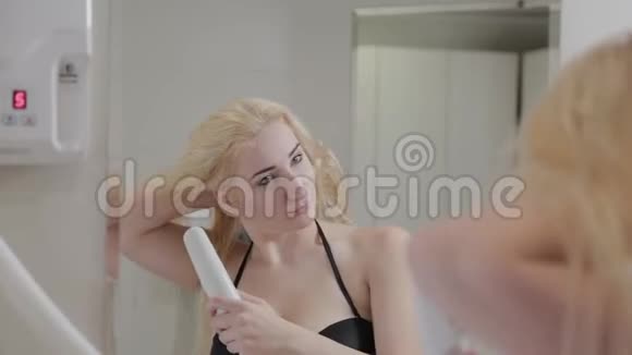 美丽的年轻女孩在水疗后用吹风机擦干头发视频的预览图