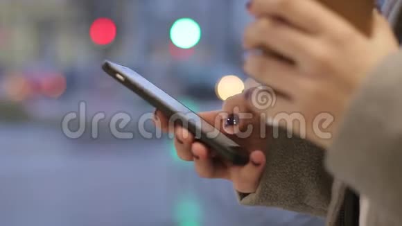 手拿着智能手机和一个咖啡杯在街上视频的预览图