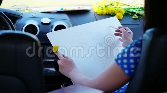 艺术家美丽的黑发女人坐在车里画铅笔素描画一束黄色的蒲公英由视频的预览图
